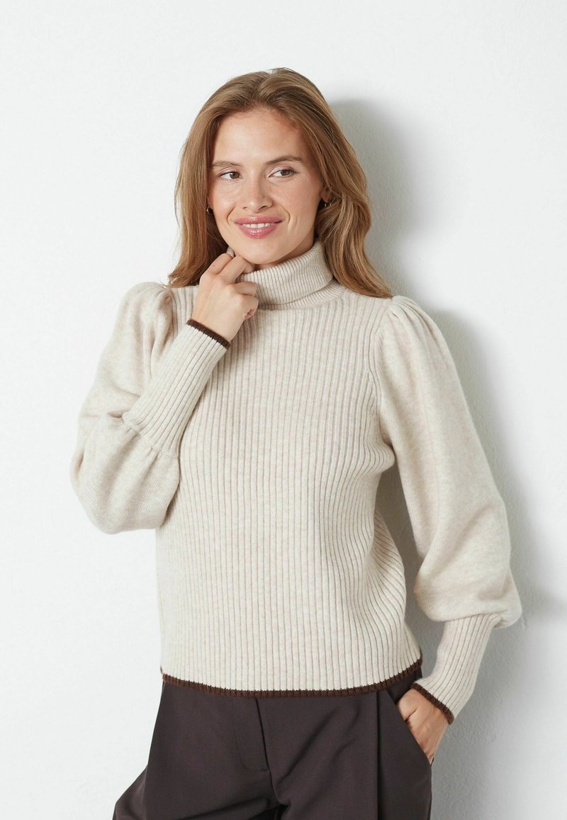 Maglione a collo alto rigato beige chiaro con maniche a sbuffo e rifiniture marroni. Texture morbida e design aderente con una vestibilità leggermente rilassata sui fianchi.