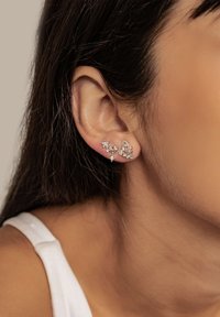 Silver earrings with star and floral designs, featuring clear gemstones. Designed for pierced ears, showcasing intricate detailing and texture.