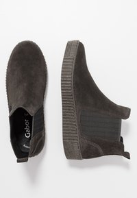 Bottines en daim noir avec panneaux latéraux élastiques et semelles en caoutchouc texturées. Caractéristiques : bout rond et languettes pour un enfilage facile.