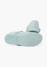 Scarpe verde menta chiaro con tomaia in tessuto liscio, strap di supporto e suola in gomma decorata con motivi floreali e a forma di cuore.