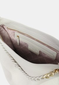 Borsa bianca con texture che presenta un bordo intrecciato, un interno foderato di rosa, una tasca con zip e un accento in catena color oro.