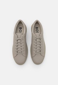 Beiga lädersneakers med en mjuk textur, platta snören och en subtil logo på tungan. Har en minimalistisk design och gummisula.