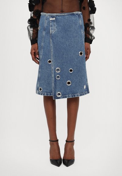 Jeansrock mit mittellanger Schnittform, metallischen Ösen und einem Schlitz vorne. Blaue Farbe mit fransigem Saum und sichtbaren Nähten.