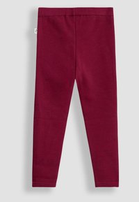 Bordo spalvos leggingai, pagaminti iš minkštos medžiagos, su elastingu juosmeniu, lygia tekstūra ir prigludusia, siaurėjančia forma. Nėra pastebimų raštų ar akcentų.