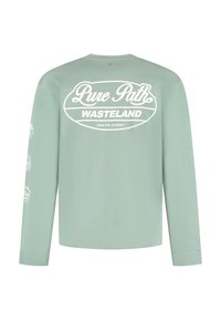 Lichtgroen shirt met lange mouwen en witte grafische tekst op de achterkant en mouwen. Zacht, lichtgewicht stof met een ontspannen pasvorm.