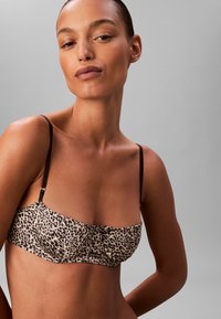 Bandeau w panterkę z cienkimi czarnymi ramiączkami, teksturowanym materiałem oraz detalem w postaci guzików z przodu. Posiada metkę z logo z boku.