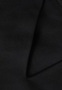 Schwarzer Stoff mit glatter Textur, der gefaltete Abschnitte und dezente Nähte aufweist und so ein geschichtetes Erscheinungsbild erzeugt.