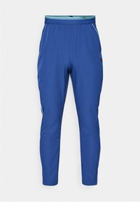 Blaue Sporthosen mit einer taillierten Passform, elastischem Bund und kontrastierenden grünen Streifen an den Seiten. Hergestellt aus leichtem Material.