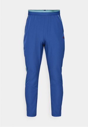 Blå sportsbukser med et taperet design, elastisk talje og kontrasterende grønne striber på siderne. Fremstillet af letvægtsmateriale.