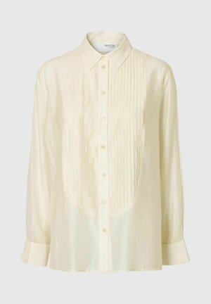 Svetlo smetanasta srajca s koničastim ovratnikom, sprednjimi gumbi in navpičnimi naborki. Narejena iz gladkega, rahlo sijočega materiala z dolgimi rokavi.