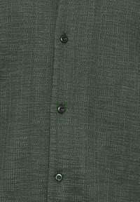 Dark green textured fabric with a subtle grid pattern, featuring a vertical row of four black buttons.