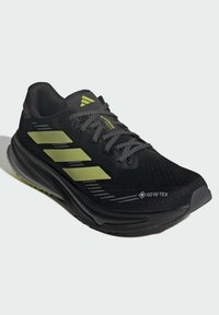 Black running shoe with olive green Adidas stripes, Gore-Tex branding, and black patterned laces, angled to show side and front.
