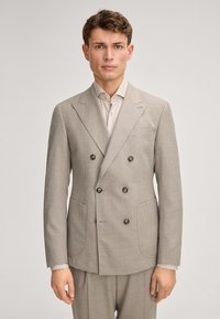 Beżowa, w kratk�ę, podwójnie zapinana marynarka z dużymi guzikami, klapami w szpic oraz dwiema przednimi kieszeniami. W komplecie z jasną koszulą.