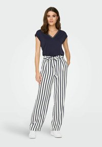 Top de punto en navy con escote en V y mangas cortas combinado con pantalones de pierna ancha a rayas en navy y blanco de cintura alta, que cuentan con un cinturón de tela anudado.