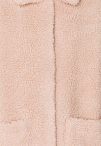 Abrigo de peluche sintético rosa con una superficie texturizada, que presenta un cuello y dos bolsillos frontales. Material suave y acolchado, con un diseño de abertura frontal.