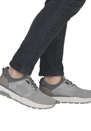 Chaussures de sport grises en mesh et suède avec une tige texturée. Semelle gris clair et lacets noirs, portées avec un jean en denim foncé.