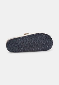 Black rubber shoe sole with a wavy textured pattern. Metallic trim along the edge. Flat profile with no visible markings or logos.
