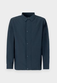 Μακρυμάνικο πουκάμισο σκούρου μπλε με υφή υφάσματος, κούμπωμα με κουμπιά μπροστά, κλασικό γιακά και πλαϊνές τσέπες σε απλό φόντο.