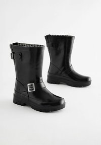 Bottines en caoutchouc noires avec une doublure houndstooth texturée, un détail de sangle ajustable et des semelles robustes à crampons pour une meilleure adhérence et stabilité.