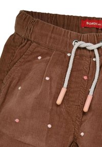 Pantaloni di velluto a coste marroni con pois pastello ricamati, vita elastica e cordino grigio con punte rosa. Etichetta "BONDI" visibile.