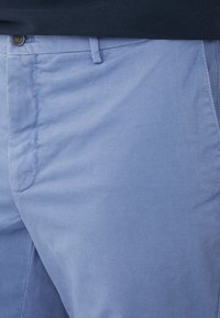 Lyseblå bomulds chinos med en glat tekstur, slim fit, frontlommer og knaplukning.
