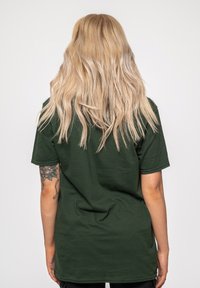 Dark green cotton t-shirt with short sleeves, relaxed fit, and a seamless neck. Features a plain back and no visible logos or graphics.