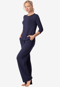 Granatowy zestaw odzieży domowej, składający się z długiego rękawa z wykończeniem w kształcie falbany i kieszeni, zestawiony z luźnymi, zwężającymi się spodniami dla komfortu.