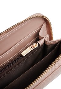 Interno di un portafoglio in pelle sintetica rosa con cerniera dorata, fodera in tessuto marrone e più scomparti per carte. Presenta dettagli di cucitura.