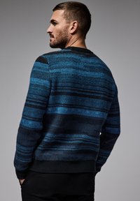 Suéter de rayas azules y negras, hecho de material de punto texturizado, con un cuello redondo y puños y dobladillo de canalé.