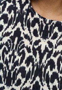 Tessuto a righe navy e crema caratterizzato da un design astratto e testurizzato con forme irregolari e piccoli dettagli ricamati.