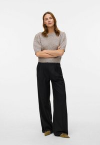 Maglione grigio chiaro a maglia con maniche a sbuffo corte, abbinato a pantaloni neri a gamba larga e ballerine verde oliva. Design pulito e minimale.