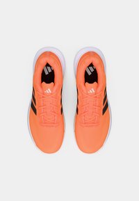 Πορτοκαλί αθλητικά παπούτσια με μαύρες ρίγες, υφασμάτινο πλέγμα με υφή στο πάνω μέρος, επενδυμένο κολάρο και λευκή σόλα. Παραδοσιακό σύστημα δέσιμου με κορδόνια στον ίδιο χρώμα.