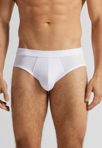 Vita bomullsboxershorts med en tight passform, som har en slät midja och en frontficka för stöd. Tyget har en mjuk, andningsbar textur.