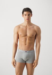 Boxers en coton gris avec une ceinture élastique à logo. Le modèle se tient debout, affichant un design ajusté et une texture douce.