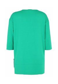 Green short-sleeve top featuring a loose fit, soft texture, round neckline, and side slit detail at the hem.