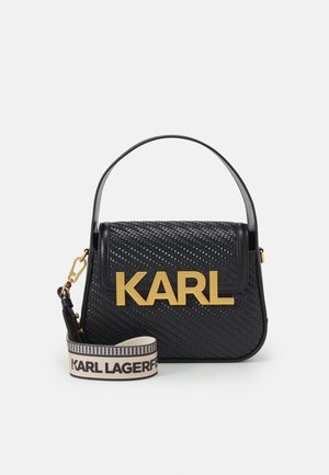 Sac à main tissé noir avec une forme structurée, présentant un logo doré à l'avant et une bandoulière amovible avec un nom de marque beige.