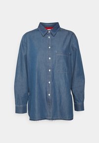 Donkerblauw denim overhemd met knopen, voorzien van een borstzak, witte stikdetails en een iets rafelige zoom. Lange mouwen met manchetten.