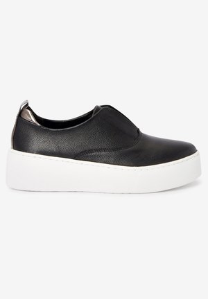 Baskets noires à enfiler avec dessus en cuir texturé, accent métallique au talon et épaisse semelle plateforme blanche sur un fond uni.