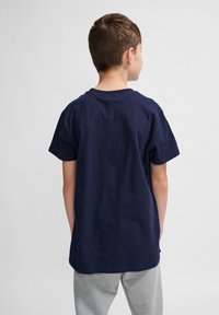 Tricou din bumbac de culoare bleu marin, cu mâneci scurte și guler rotund, văzut din spate. Croi lejer, fără motive sau grafice vizibile.