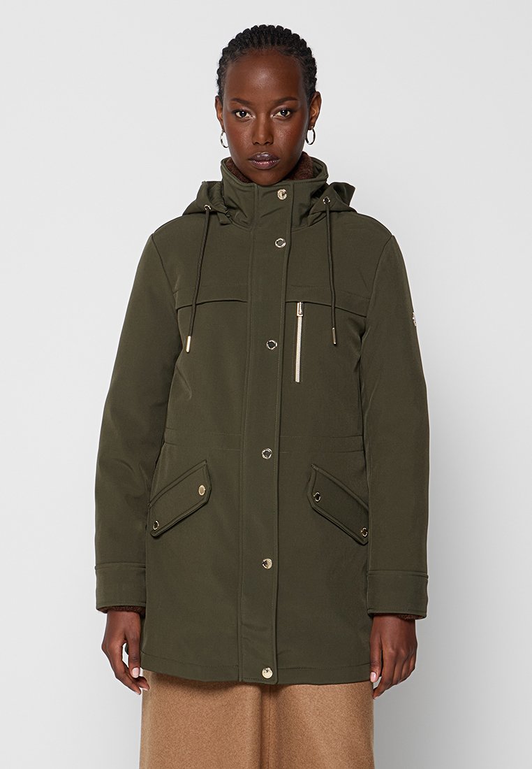 Giacca parka verde oliva con cappuccio, realizzata in tessuto morbido, presenta chiusure con zip e bottoni a pressione, due tasche frontali e regolazione con cordino nel cappuccio.