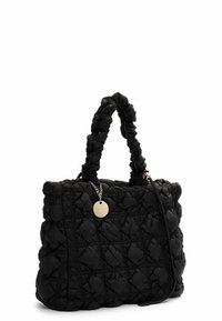 Schwarze gesteppte Handtasche mit gepolsterten Griffen und einem runden goldenen Anhänger, der an einer silbernen Kette an einem weißen Hintergrund hängt.