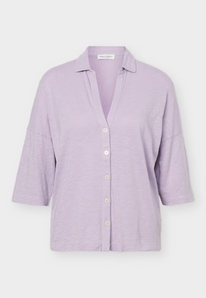 Lyse lilla skjorte med knapper, korte ærmer og en afslappet krave, lavet af tekstureret stof.