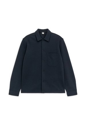 Mørkeblå langærmet skjorte med knapper, krave og enkelt brystlomme, lagt fladt ud på hvid baggrund.