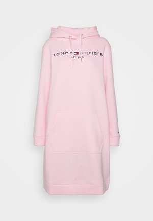Robe sweat à capuche rose avec une poche avant, logo "TOMMY HILFIGER EST. 1985" en navy, et cordons avec embouts métalliques. Texture de tissu douce.