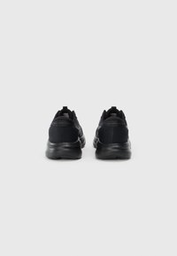 Zapatos deportivos negros con parte superior de malla, cuello acolchado y suela amortiguada, con un logo sutil y acentos reflectantes en el talón.