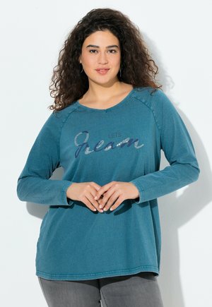 Teal langarm shirt met een ronde hals, met de tekst "LET'S JEANS" in donkerblauw en zilveren accenten. Zachte textuur, relaxte pasvorm en heuplengte.