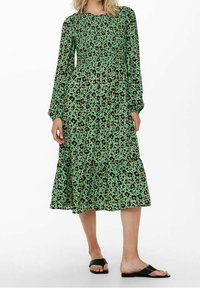 Grünes Leopardenmuster-Midi-Kleid mit langen Puffärmeln und gesmocktem Oberteil. Besitzt einen gestuften Rüschen-Saum und aus weichem, leichtem Stoff.