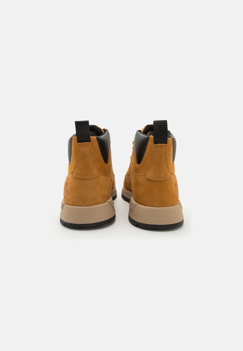 Botas de tobillo de ante marrón con parte superior de material sintético negro, suela de goma, lengüetas en el talón y detalle del logo en el tacón.