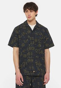 Camicia a maniche corte di colore blu scuro con stampa astratta a motivo leopardato verde e blu, dotata di colletto classico e due tasche sul petto.