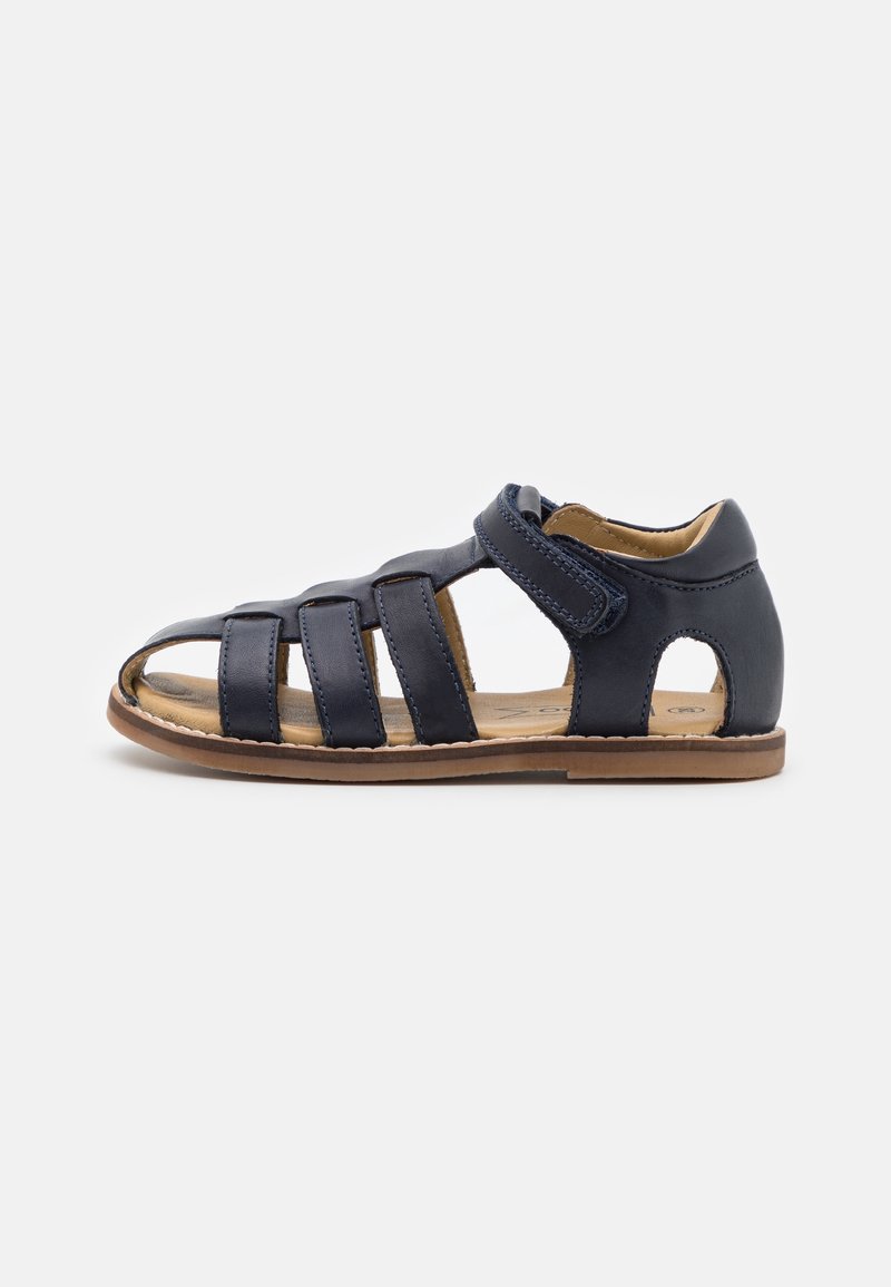 Sandale en cuir bleu marine pour enfant, avec plusieurs brides, talon fermé et fermeture Velcro réglable sur semelle couleur sable.